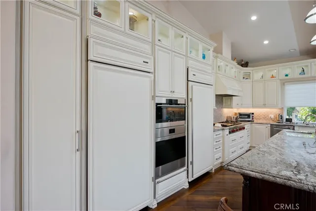 a living room with stainless steel appliances wooden floors and couches