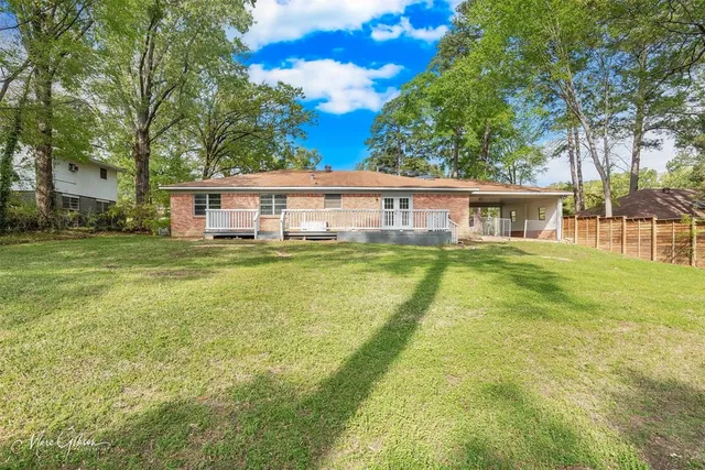a view of a house with a big yard and large trees