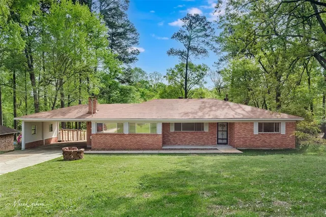 a front view of a house with a garden and trees