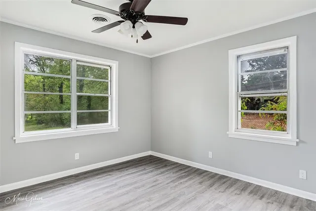 a view of an empty room with a window and wooden floor