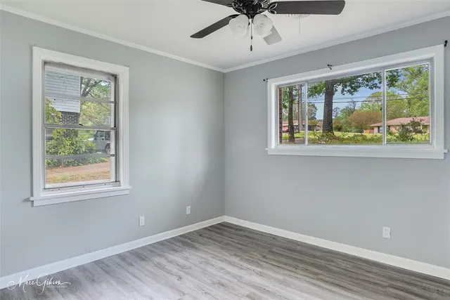 a view of an empty room with a window and wooden floor