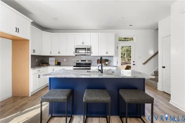 a kitchen with stainless steel appliances a white table and chairs in it