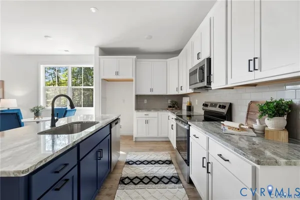 a kitchen with granite countertop a sink stainless steel appliances and white cabinets