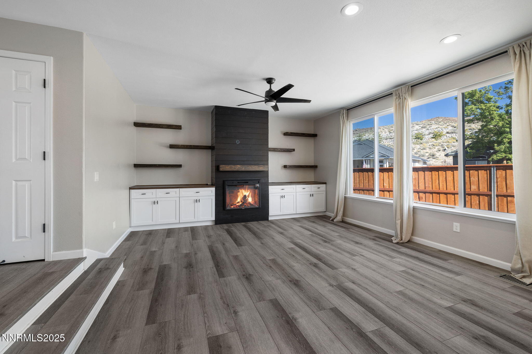 7510 Michaela Drive Reno, NV 89511 - Photo 5 of 33 an empty room with wooden floor fireplace and windows