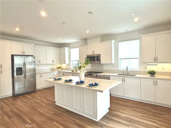 a kitchen with white cabinets appliances and wooden floor