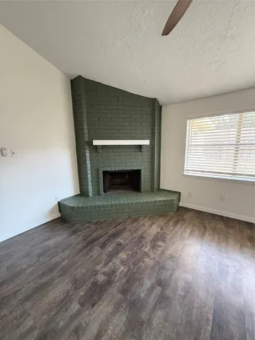 an empty room with wooden floor fireplace and windows