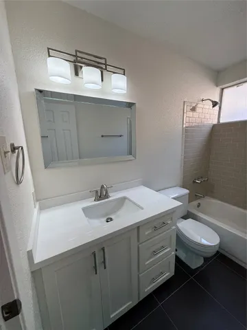 a bathroom with a granite countertop sink toilet and mirror