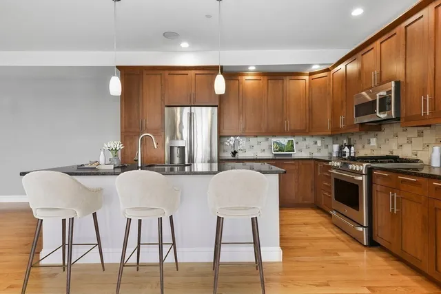 a kitchen with stainless steel appliances kitchen island granite countertop a stove a sink and a refrigerator