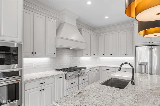 a kitchen with granite countertop a sink stainless steel appliances and cabinets