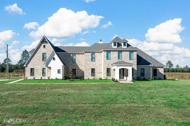 a view of a house with a big yard and large trees