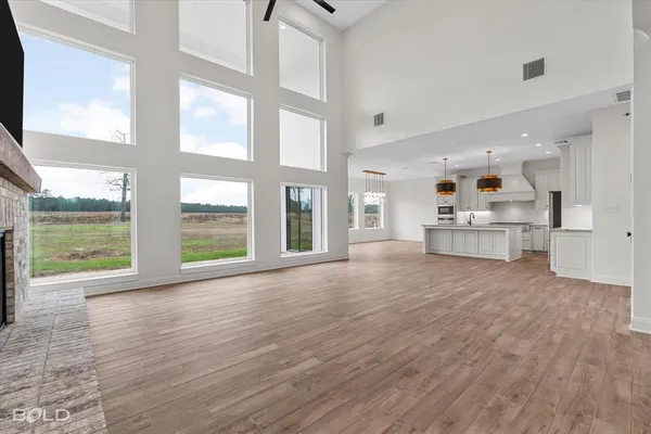 a view of an empty room with a large window and wooden floor