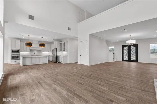 a view of an empty room with kitchen and window