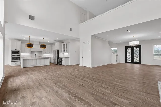 a view of an empty room with kitchen and window