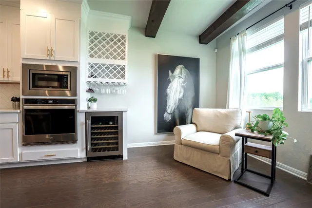 a living room with stainless steel appliances kitchen island a table chairs and a chandelier
