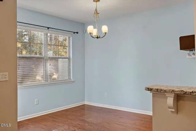 a view of an empty room with wooden floor and a ceiling fan