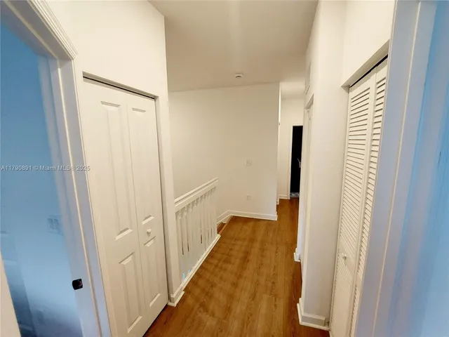 a view of a hallway with wooden floor and staircase
