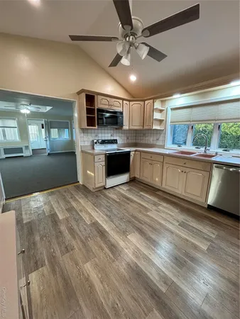 a large kitchen with kitchen island a stove a sink dishwasher a dining table and chairs with wooden floor