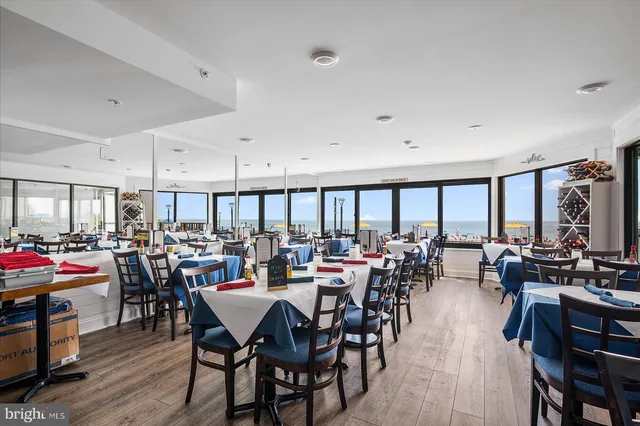 a dining area with stainless steel appliances kitchen island granite countertop a dining table chairs and a refrigerator