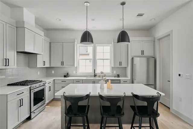 a kitchen with stainless steel appliances a dining table chairs and white cabinets