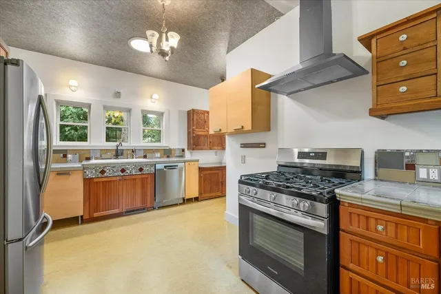 a kitchen with stainless steel appliances granite countertop a stove a sink dishwasher a refrigerator and a stove with wooden floor
