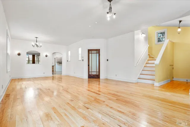 a view of an empty room with wooden floor and stairs