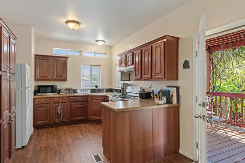 a kitchen with stainless steel appliances granite countertop wooden cabinets a refrigerator a sink a stove a microwave and wooden floors