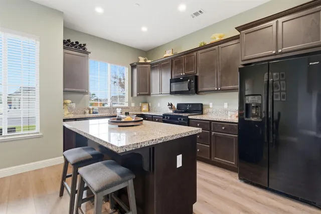 a kitchen with kitchen island granite countertop a sink stove and refrigerator