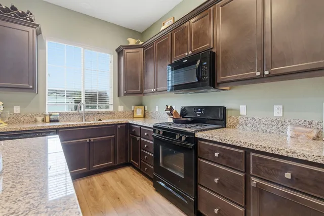 a kitchen with stainless steel appliances granite countertop white cabinets granite counter tops and a window