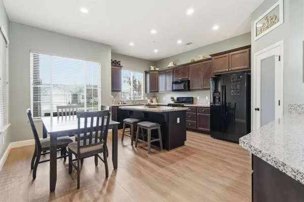 a kitchen with stainless steel appliances granite countertop a refrigerator a stove a sink a dining table and chairs