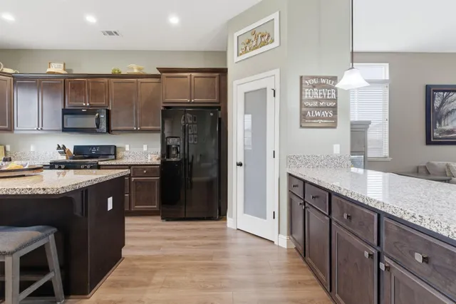 a kitchen with stainless steel appliances granite countertop a refrigerator a sink and a stove