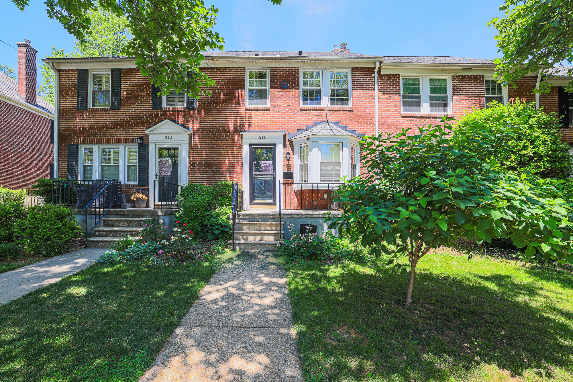 Charming brick rowhouse with lush greenery.