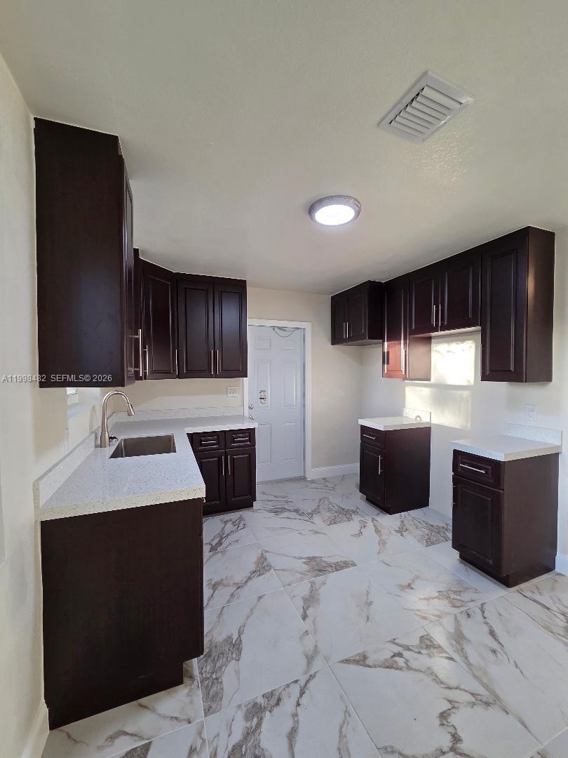 295 Northwest 48th Street Miami, FL 33127 - Photo 5 of 12 a kitchen with stainless steel appliances kitchen island granite countertop a sink a stove and refrigerator