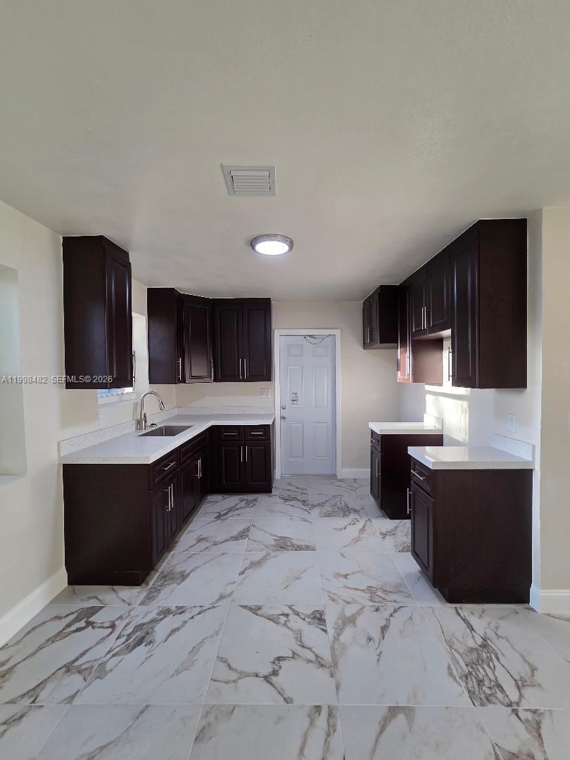 295 Northwest 48th Street Miami, FL 33127 - Photo 7 of 12 a large kitchen with stainless steel appliances kitchen island granite countertop a sink and cabinets