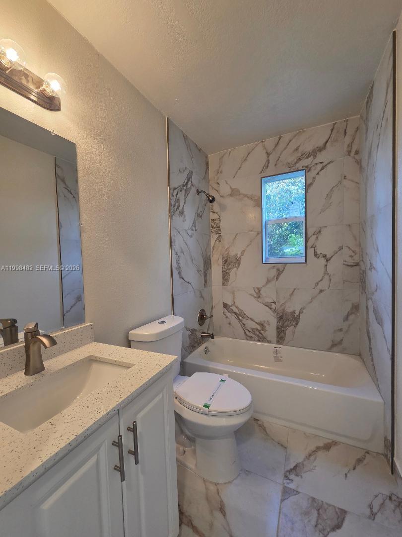 295 Northwest 48th Street Miami, FL 33127 - Photo 9 of 12 a bathroom with a granite countertop sink a toilet and bathtub