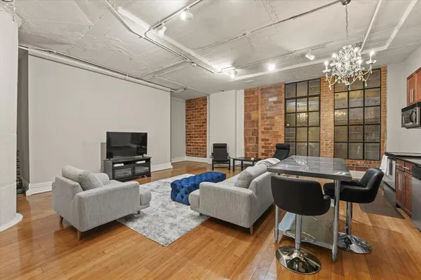 a living room with furniture a chandelier a large window and wooden floor