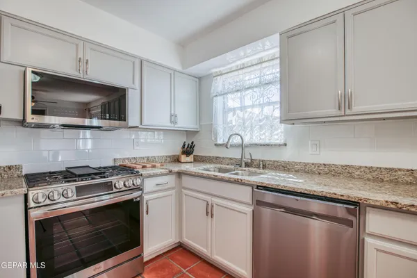 a kitchen with granite countertop a stove a sink and dishwasher a microwave oven with cabinets