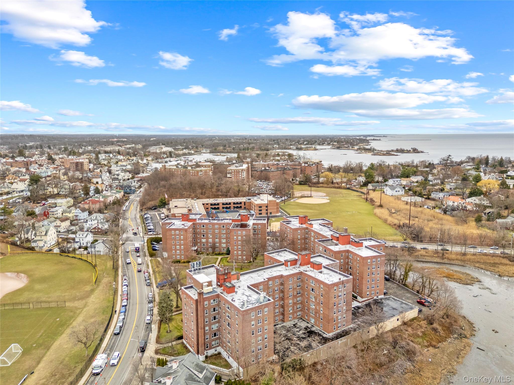 230 Pelham Road, Unit 4L New Rochelle, NY 10805 - Photo 6 of 30 Aerial view of the building complex with scenic views of Hudson Park and Five Islands Park in the background, showcasing the property’s proximity to waterfront parks, green space, and coastal recreation.