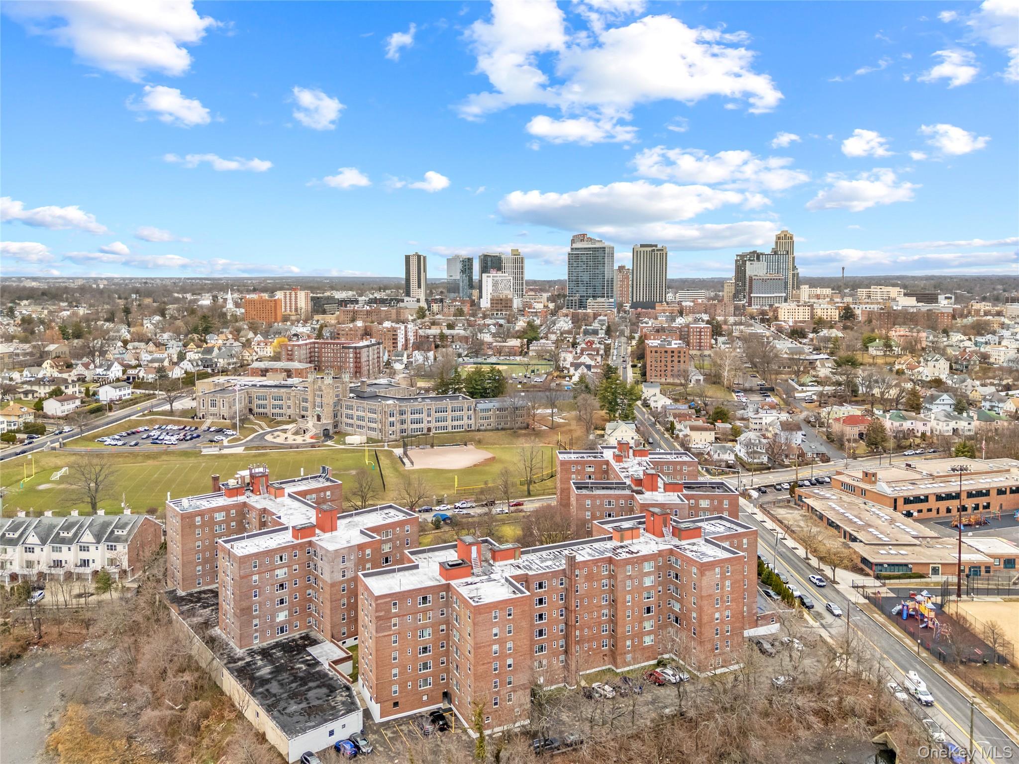 230 Pelham Road, Unit 4L New Rochelle, NY 10805 - Photo 9 of 30 Aerial view of the building complex with the vibrant skyline of downtown New Rochelle in the background, highlighting the property’s convenient location near shopping, dining, transportation, and the waterfront.