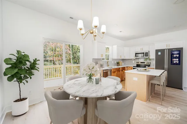 a living room with stainless steel appliances kitchen island furniture and a chandelier