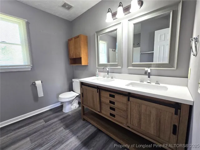 a bathroom with a double vanity sink a toilet and a mirror