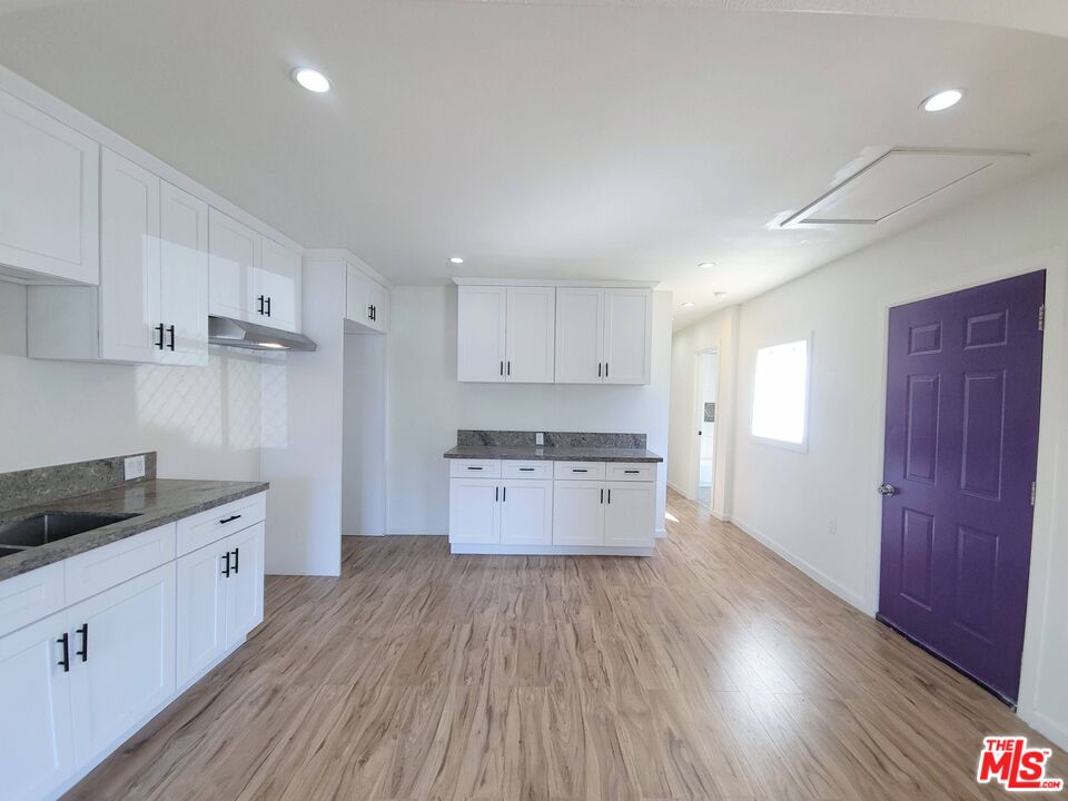 200 North Acacia Avenue Compton, CA 90220 - Photo 4 of 18 a kitchen with a wooden floor and cabinets