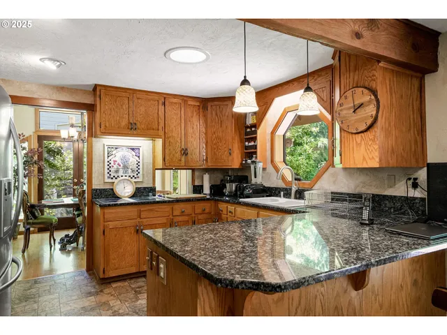 a kitchen with kitchen island granite countertop a stove a sink and a wooden cabinets