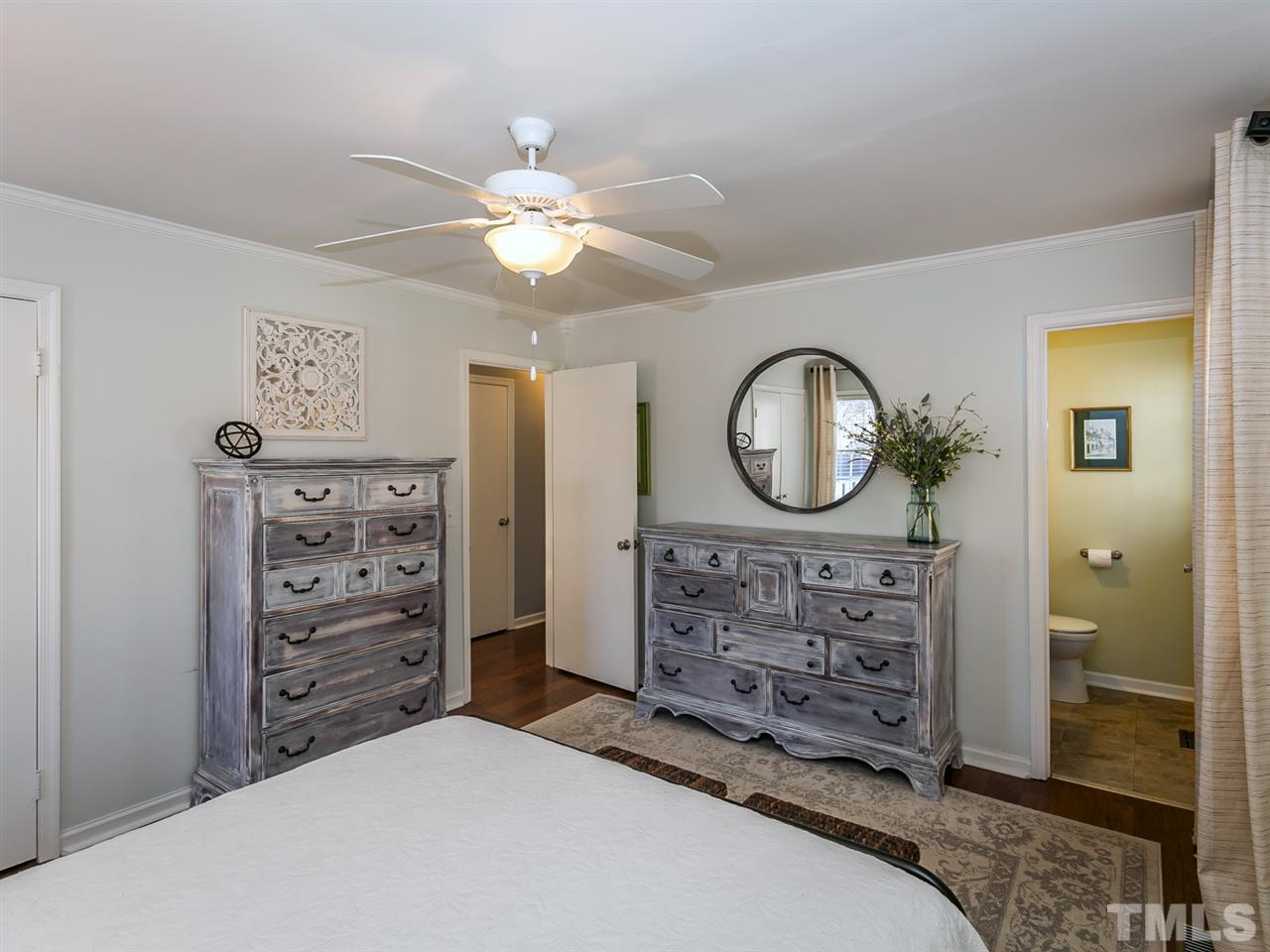 7705 Prospector Place Raleigh, NC 27615 - Photo 14 of 30 a bedroom with a bed a mirror on dresser and a chandelier