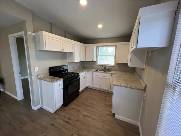 a kitchen with granite countertop a sink a counter top space stainless steel appliances and cabinets