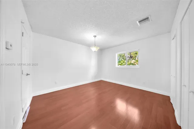 an empty room with a fan & a window