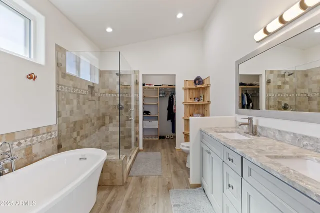 a spacious bathroom with a granite countertop tub sink a mirror a shower and vanity