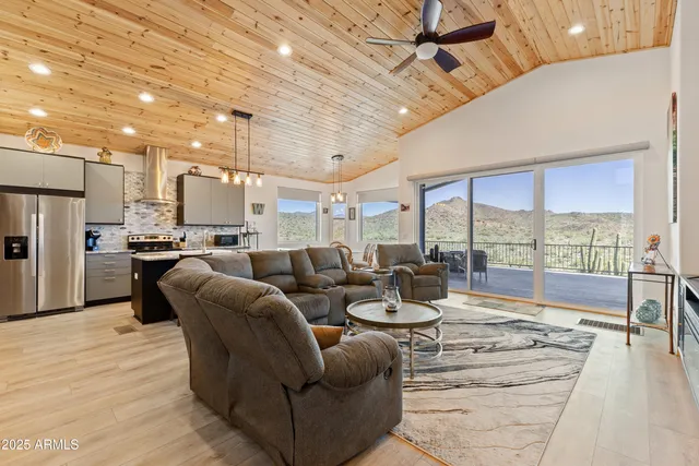 a living room with furniture and a large window with kitchen view