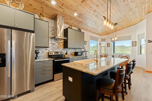 a kitchen with stainless steel appliances granite countertop a table chairs stove and refrigerator