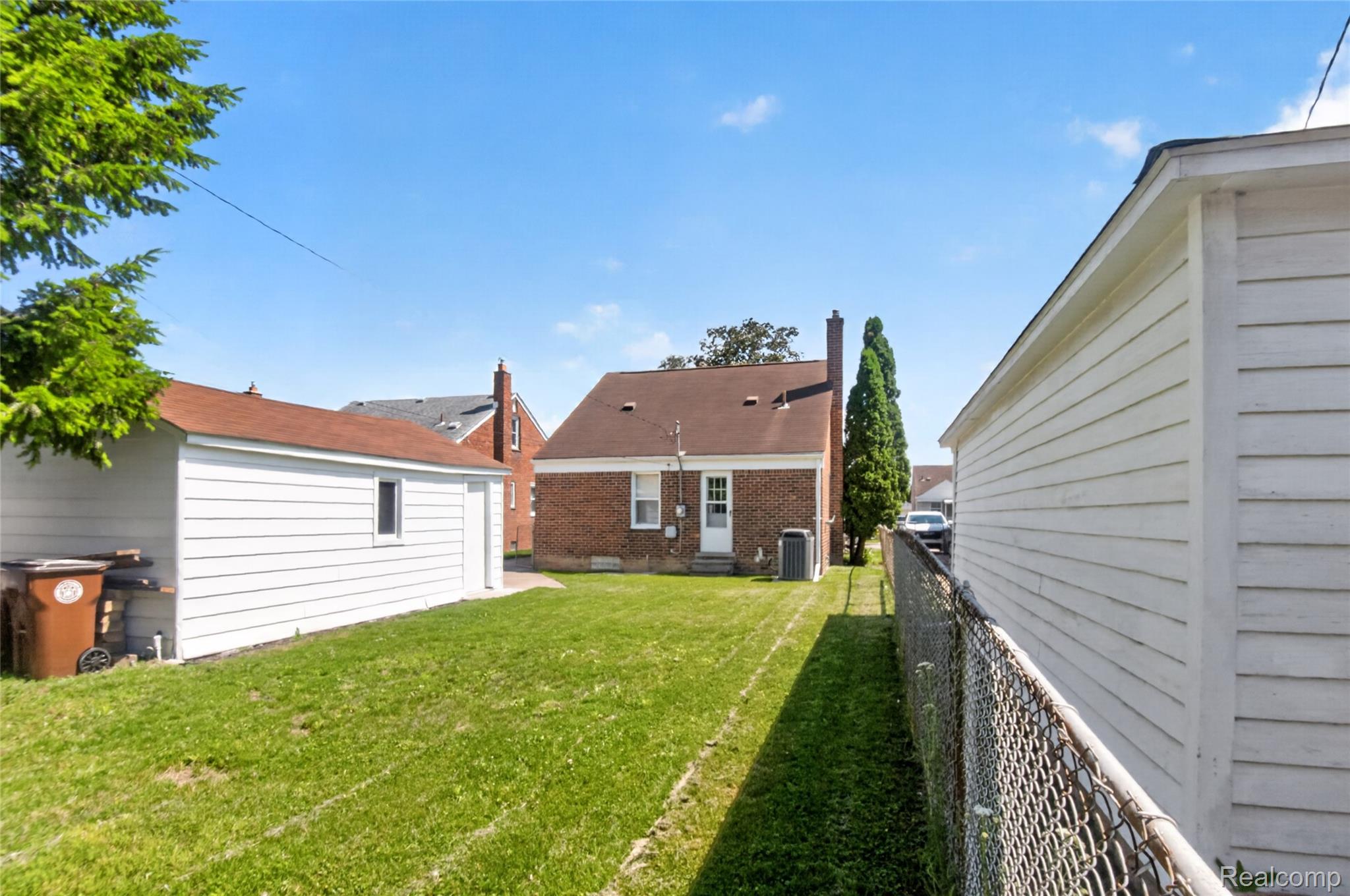 12972 Callender Street Southgate, MI 48195 - Photo 36 of 40 Fenced backyard featuring a detached garage with white siding, a brick exterior home, and mature landscaping