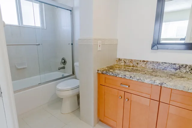 a bathroom with a granite countertop toilet a sink and a bathtub